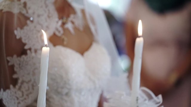 Bride and groom holding candles in church at christianity wedding ceremony