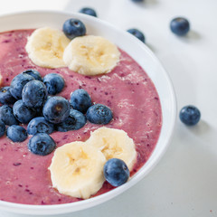 Vegan fruit smoothie with blueberries and banana on white background, close-up, day