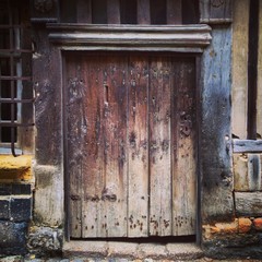 Fototapeta na wymiar Ancient weathered wooden doorway in Honfleur, Normandy, France. Mobile phone photo with some phone or tablet post processing.