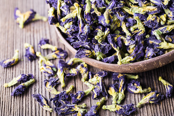 Dried blue butterfly pea flowers on wooden background.