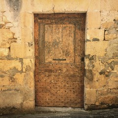 An ancient studded wooden doorway on the side of a house in St Cyprien, Dordogne, France. Security concept. Mobile phone photo with some phone or tablet post processing.