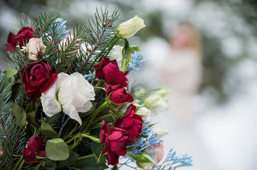 Close up of beautiful wedding bouquet with colorful flowers, pink and red roses on snow. Long ribbons around. Winter wedding and season floral concept.