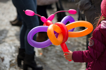 A small girl holding a balloon butterfly or dog that she got as a gift for her birthday party at a children party from clown  
