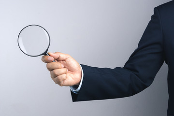 Business man hand holding magnifier for inspection