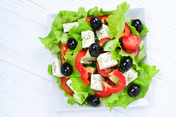 Greek salad on a white wooden background. Space for text or design.