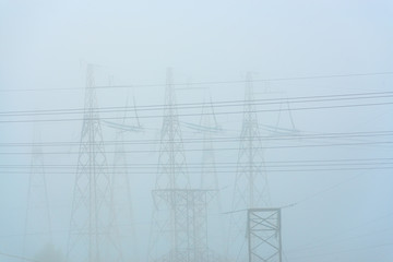 High voltage transmission towers in meadow at orange sunset 

