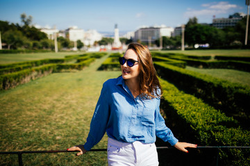 Woman smiling in sunglasses with perfect smile and white teeth in a park and looking at camera on garden background