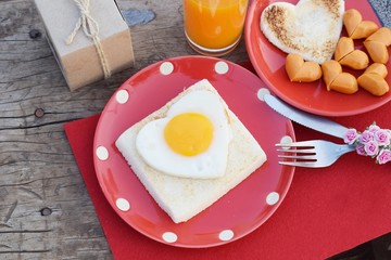 heart shape sunny side up egg with sausage on red dish with orange juice, valentine breakfast concept