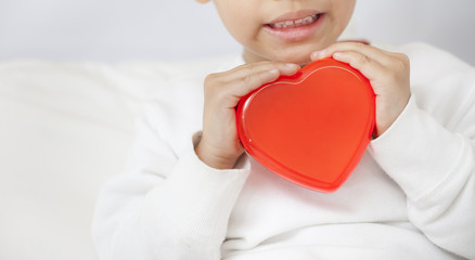 Child holding small red heart, closeup..