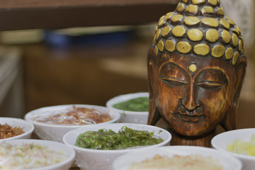 Statue of wooden buddha on a thai food preparation table