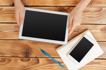 woman holding blank tablet device over a wooden workspace table