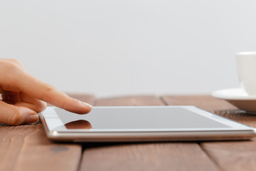 woman holding blank tablet device over a wooden workspace table