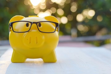 yellow piggy bank wear glasses on blurred bokeh background, smart investment concept
