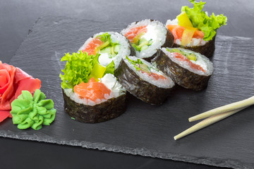 Japanese restaurant, sushi roll on black slate plate.