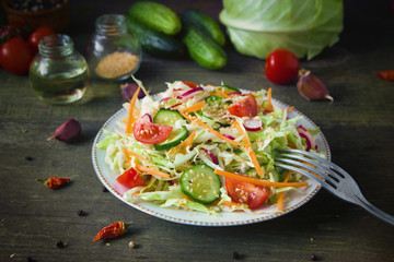 Fresh dietary salad of cucumbers, tomatoes, cabbages, radishes, carrots with sesame seeds, olive oil, garlic and herbs. Healthy meal. Detox and vegetarian concept.