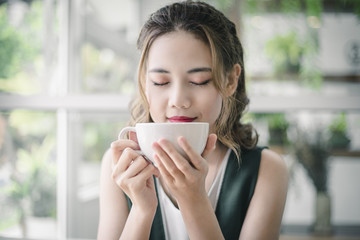 Beautiful Asian girl drink a cup of coffee in the morning
