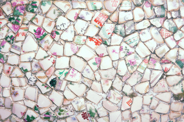 Mosaic made of broken crockery and tableware background. Wall tiled with ceramic pieces having floral pattern and Chinese hieroglyphs meaning: rich, blessing, tea, four