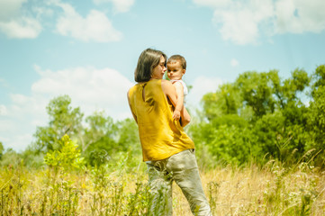 mother holding son in field at sunny day