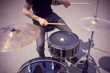 Obraz premium cropped shot of tattooed drummer playing drums on street