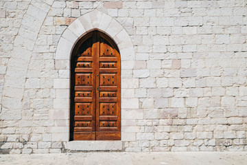Fototapeta premium Old brick wall and wooden door in Assisi, Italy