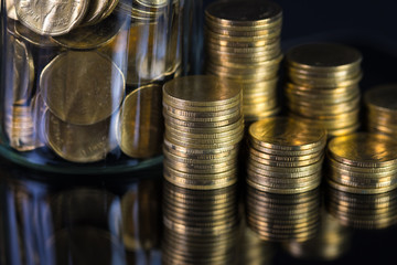 Coins stacks and gold coin money in the glass jar on dark background, for saving for the future banking finance concept.