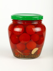 Jar of pickled small red cherry tomatoes on white