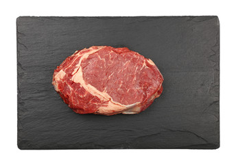 Close up raw beef ribeye steak on slate board