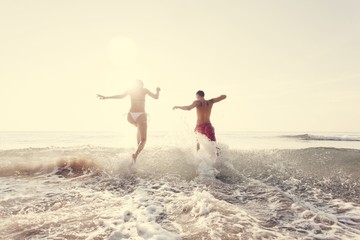 Happy couple running into the water