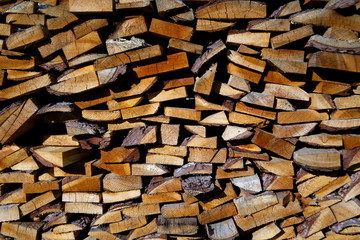 Wooden background of firewood stacked in a woodpile on a farm