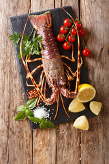 Gourmet food: raw spiny lobster or sea crawfish with ingredients for cooking close up on a table. Vertical top view