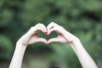 Female hand showing heart shape gesture.