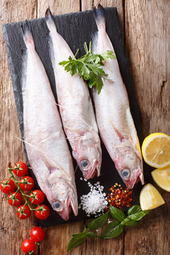 Phycis phycis, the&nbsp;forkbeard with spices, vegetables ingredients close-up on a table. Vertical top view