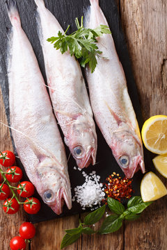 Raw Forkbeard or mostella fish with ingredients close-up on the table. Vertical top view