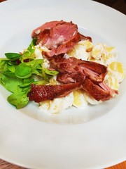 Fried duck pieces on dumpling in creamy souce .