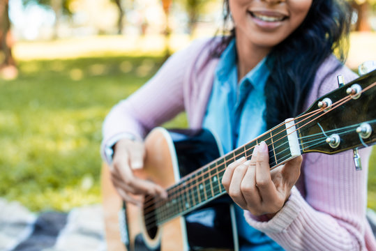 Cropped Image Of African American Woman Playing Acoustic Guitar In Park