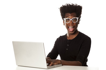 Smiling and positive happy young african-american guy using laptop computer, working project at desk on white background