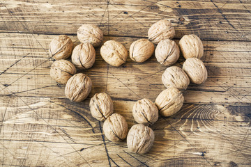 Walnuts in a heart shape on dark vintage wooden background. Healthy walnut nutrition