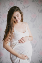 Young beautiful pregnant woman posing in a white dress