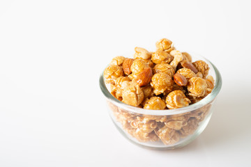 Caramel popcorn with cashew nuts and almonds in a white background, selective focus.