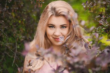 Portrait Beautiful young blonde girl with puffy lips and sexy feminine body posing in the green...