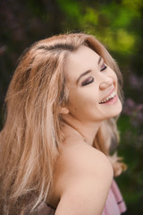 Fototapeta premium Portrait Beautiful young blonde girl with puffy lips and sexy feminine body posing in the green park on sunny day 