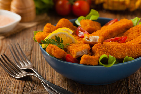 Fish sticks with salad in blue bowl.