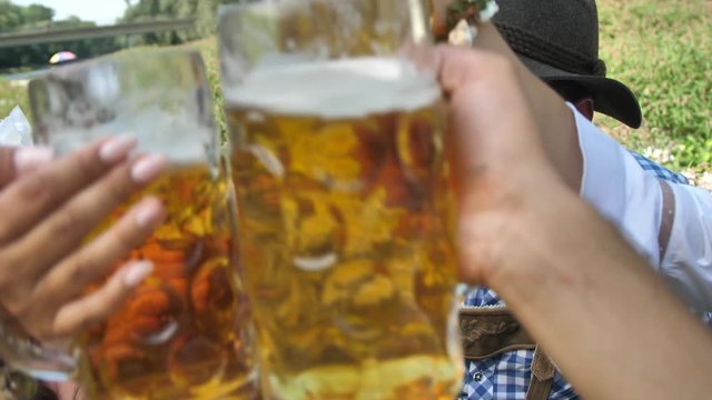 Oktoberfest Freunde in Lederhosen und Dirndl trinken Bier an der Isar