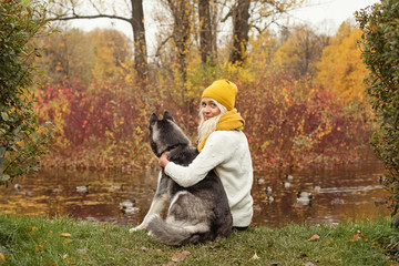 Young woman with her dog husky outdoors on autumn background