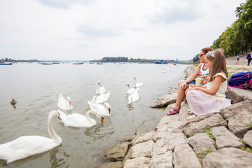 Family Feeding Swans On River