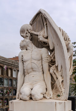 The Kiss Of Death Statue In Poblenou Cemetery In Barcelona This Marble Sculpture Depicts Death As A Winged Skeleton Kissing A Handsome Young Man The Sculpture Is At Once Romantic And Horrifying