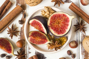 Fig walnuts cinnamon anise on a plate of old wooden background.