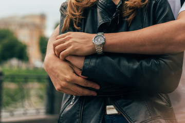 the guy is behind and hugs the girl, hands together.on the hand of a guy wearing watch.date.male...