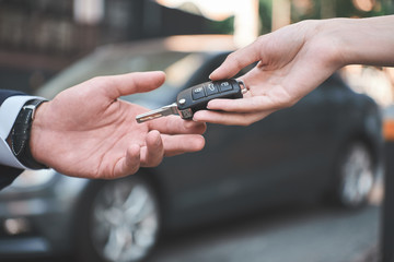 Fototapeta na wymiar Car dealership.Young man receiving car key from saleswoman.