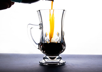transparent crystal cup and dark liquid, on white background.